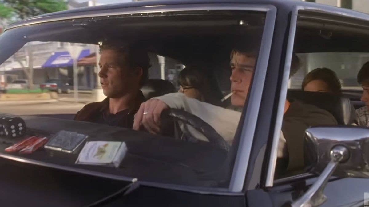Zeke Tyler driving a car with a cigarette hanging from his mouth.
